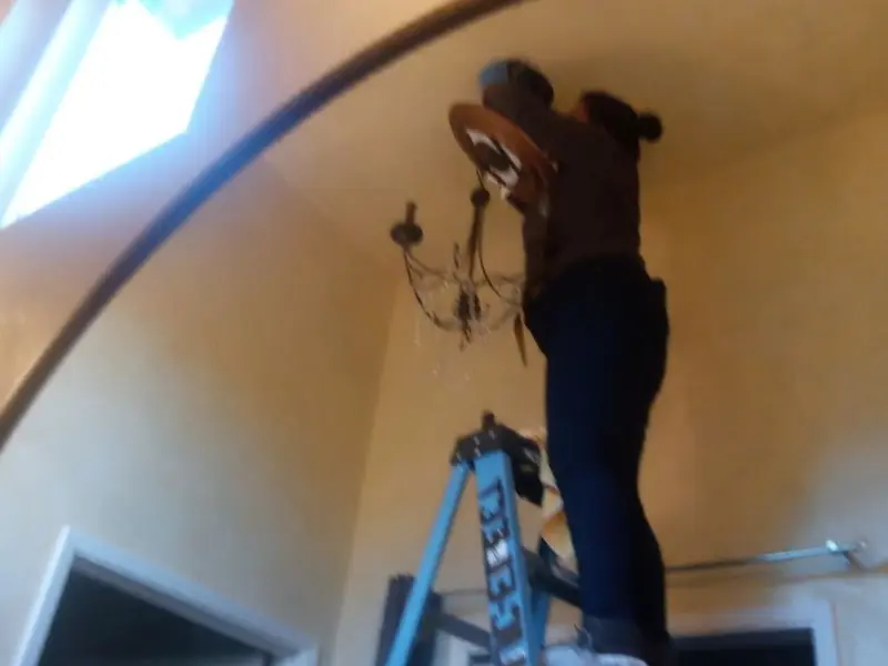 Electrician installing a chandelier in a Moraine residence